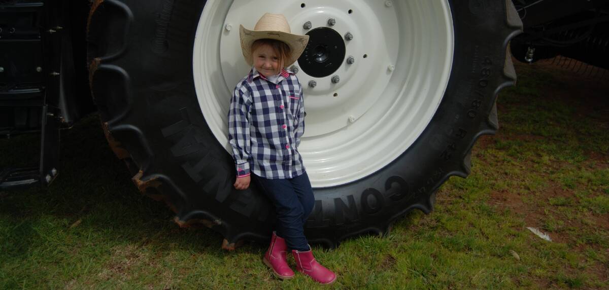 2015 SHOW: Ella had a "wheelie" good time at last year's Show. Here she is posing on the tyre of a Gerinimo Machinery tractor. Photo: GRACE RYAN. 