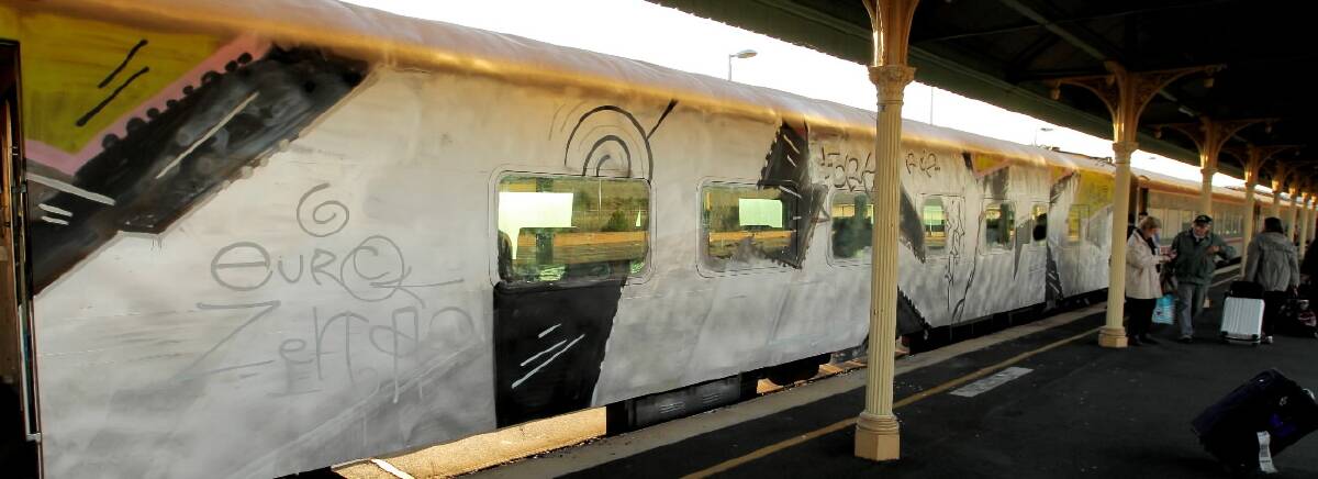 BELOW and LEFT: Passengers walk past the extensive section of spray paint on the train, with the platform at the station also covered in paint.