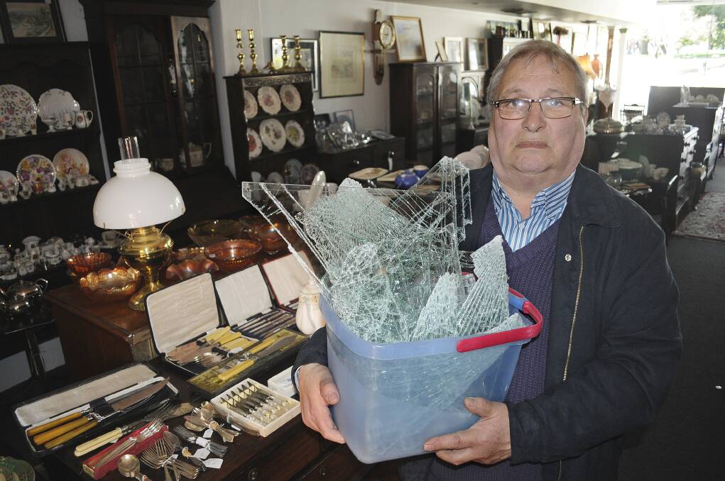 SHATTERED: Martin King of Kings Antiques, which suffered a break-in on Saturday morning, with the smashed window pane from the rear door. Photo: CHRIS SEABROOK 	090814cking1