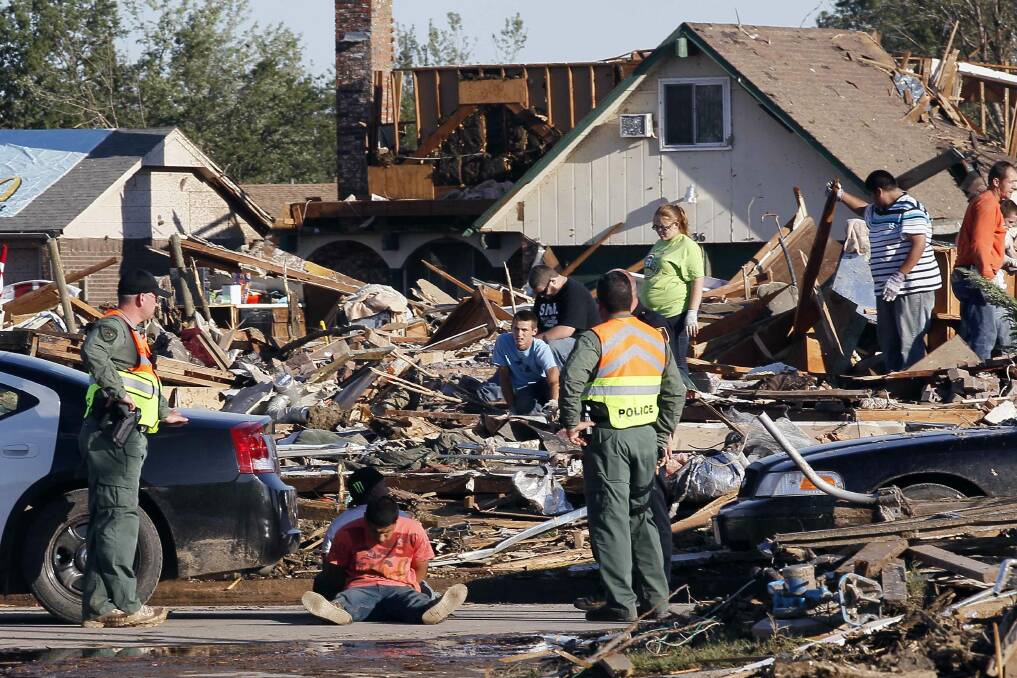 Police stand beside two men sitting handcuffed on the street whom they have detained on suspicion of looting in Moore, Oklahoma May 21, 2013. Photo: REUTERS/Rick Wilking