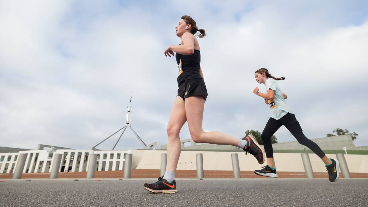 Women running past Parliament House. Picture: Sitthixay Ditthavong