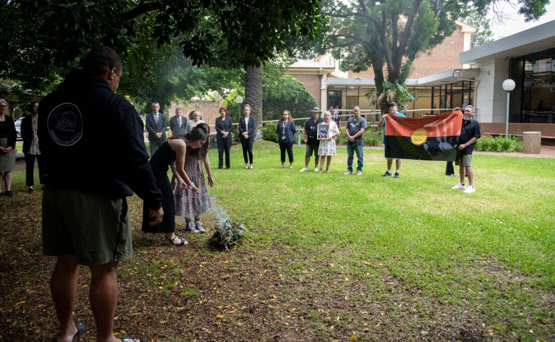Family and friends of Brandon Rich stand around and perform a smoking ceremony. Picture by Belinda Soole 
