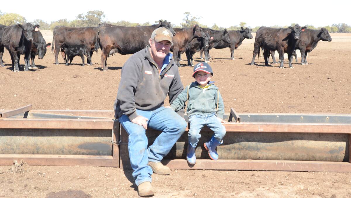 Steve Chase and son, Patrick, 3, rest between feeding their Angus breeders at Waitara, Trangie.
