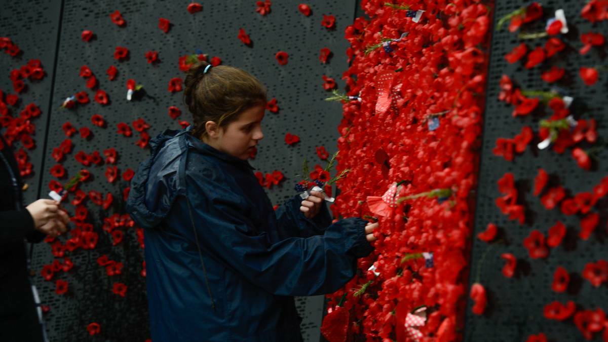 REMEMBERING: A girl places a poppy to remember the fallen. Photo: JUSTIN MCMANUS